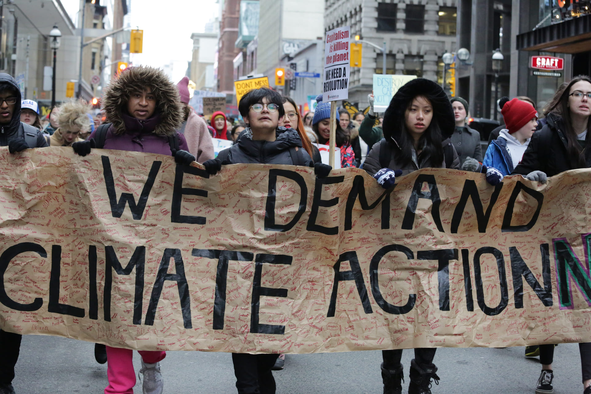 Activists and students holding signs march on the streets of downtown Toronto during a climate change rally on Black Friday