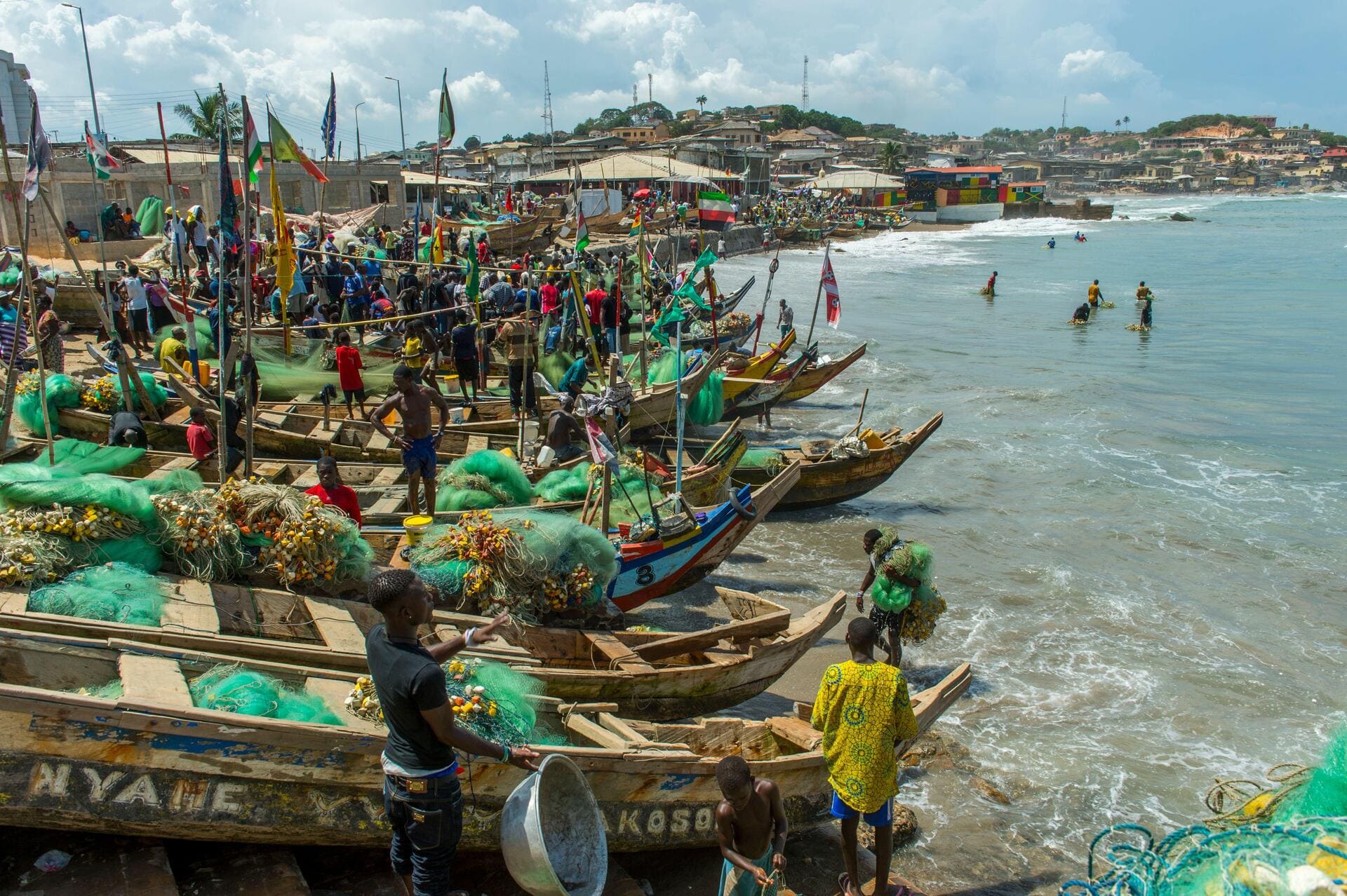 Busy beach with fishing boats and people below Cape Coast Castle near Elmina, Ghana