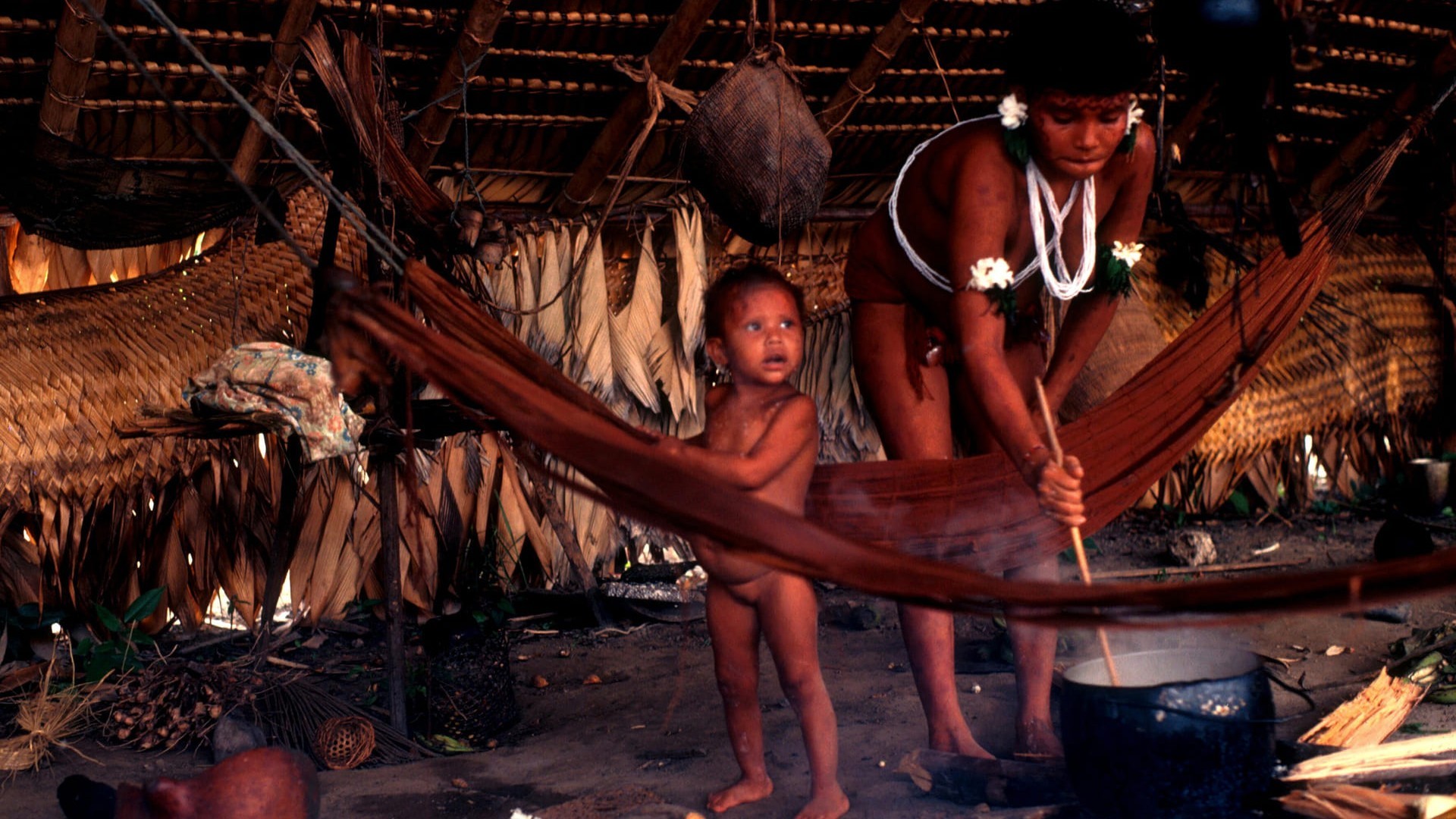 Yanomami Indian woman cooking stirring pot with infant nearby Brazil South America 