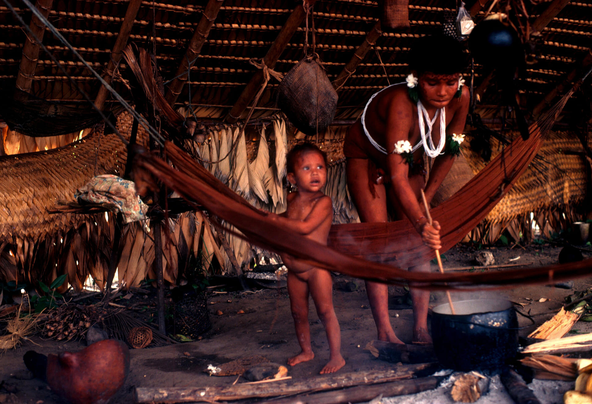 Yanomami Indian woman cooking stirring pot with infant nearby Brazil South America